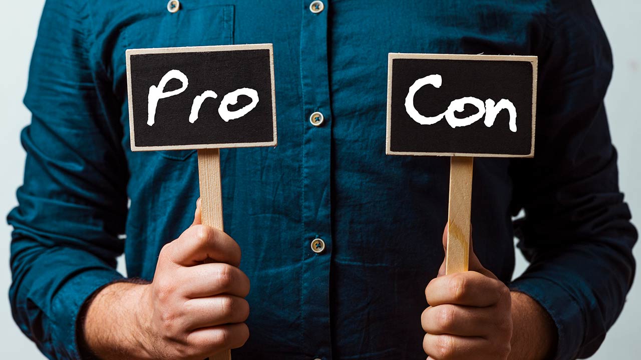 Photo of a man holding pros and cons cards