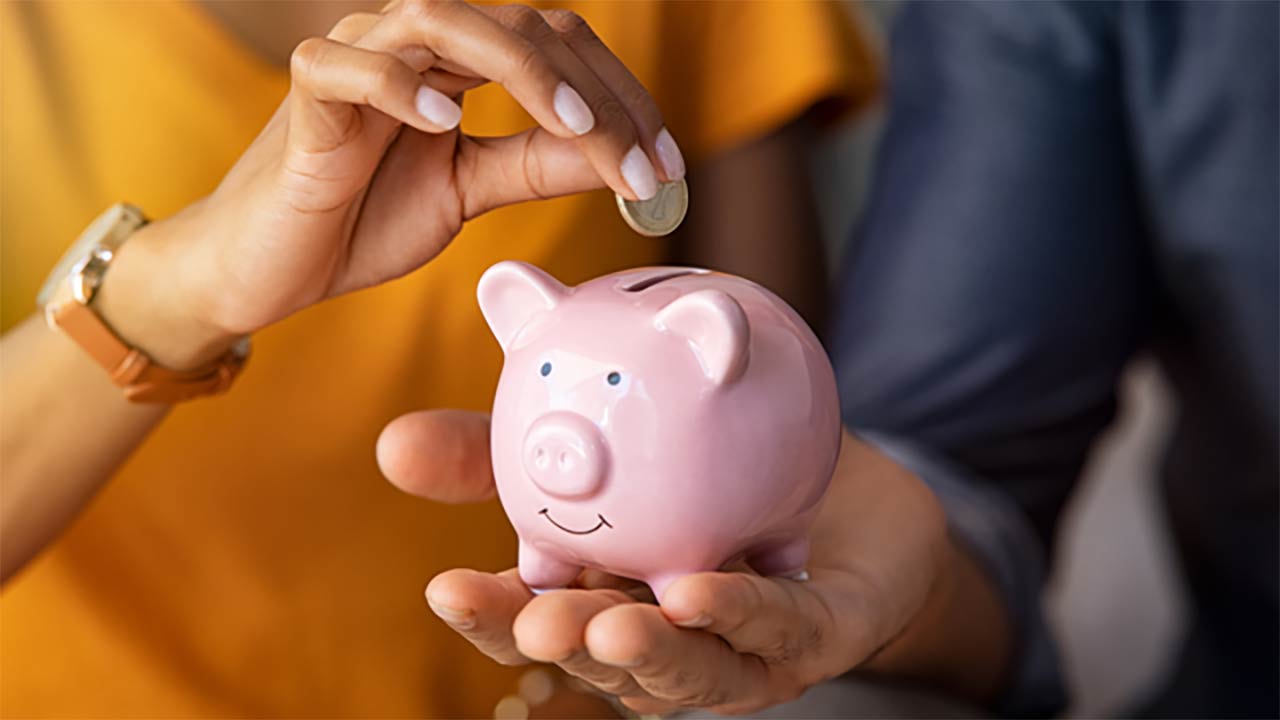 Couple inserting money into a piggybank