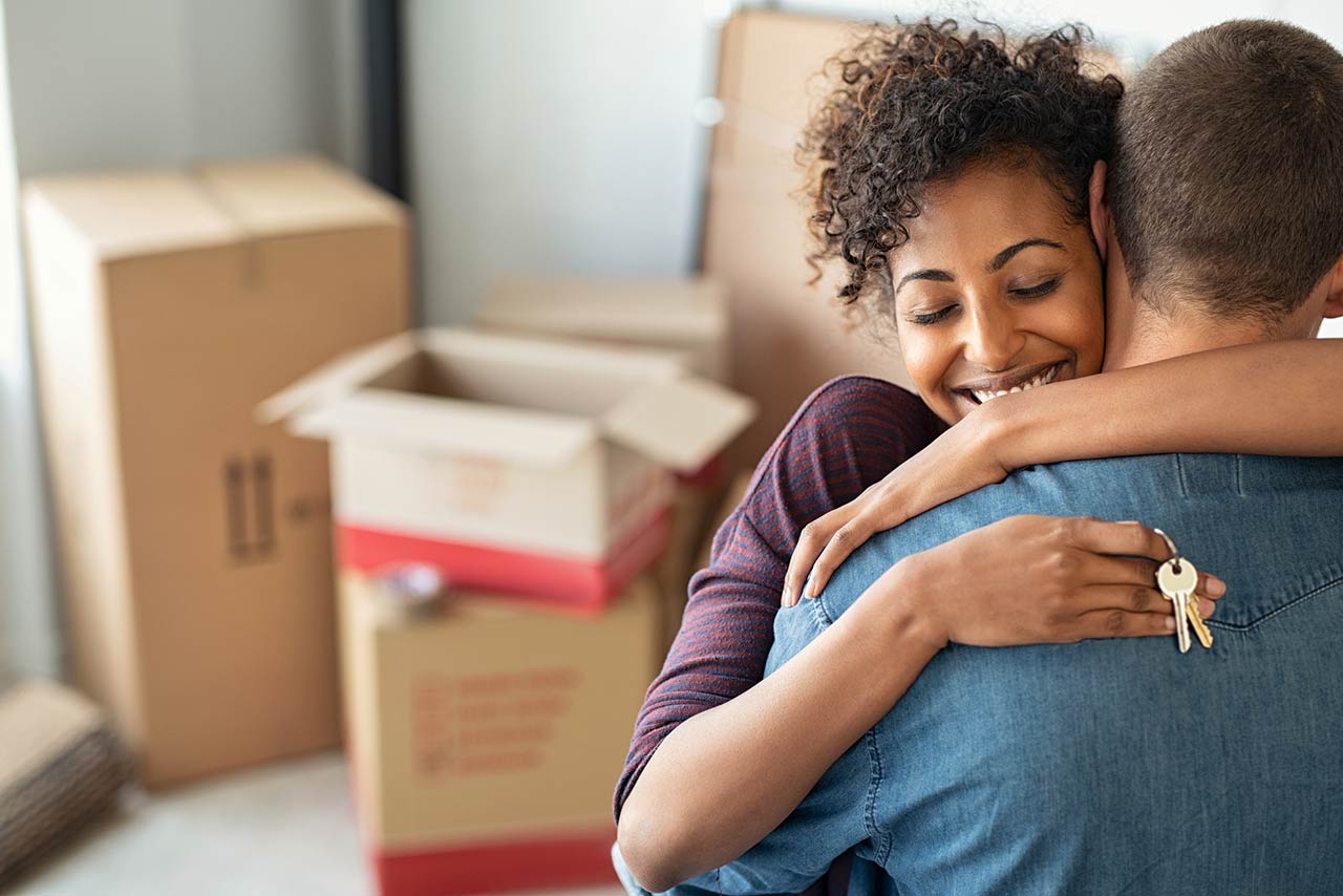 Woman holding keys from new home and embracing man