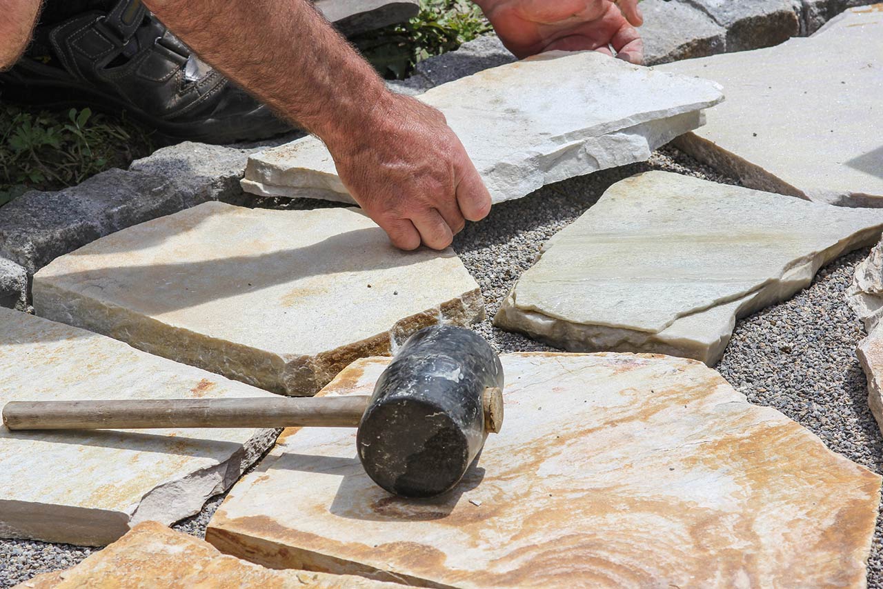 Worker is paving a place in the garden.