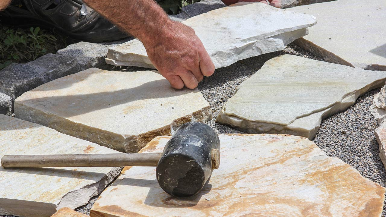 Worker is paving a place in the garden.