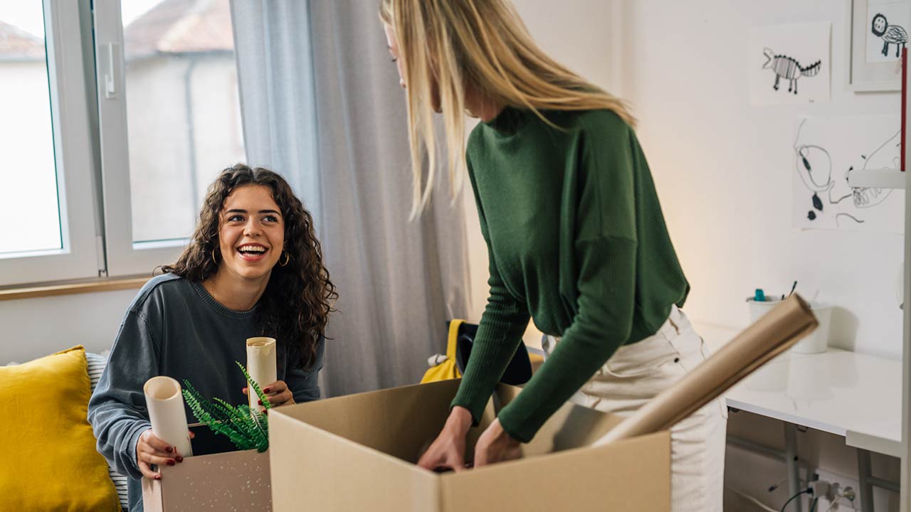 Caucasian female students unpacking in students room