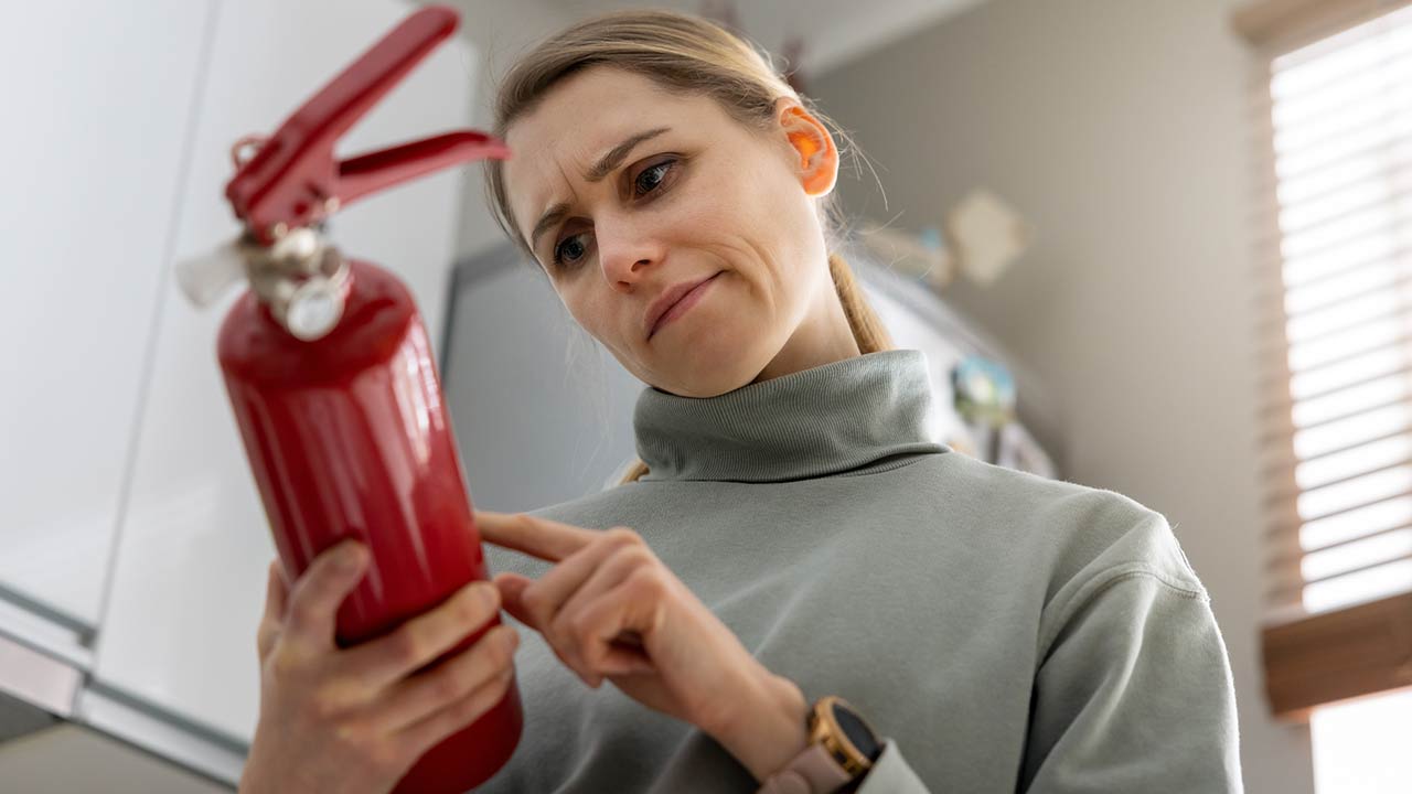 A woman checks the fire extinguisher expiration date at home