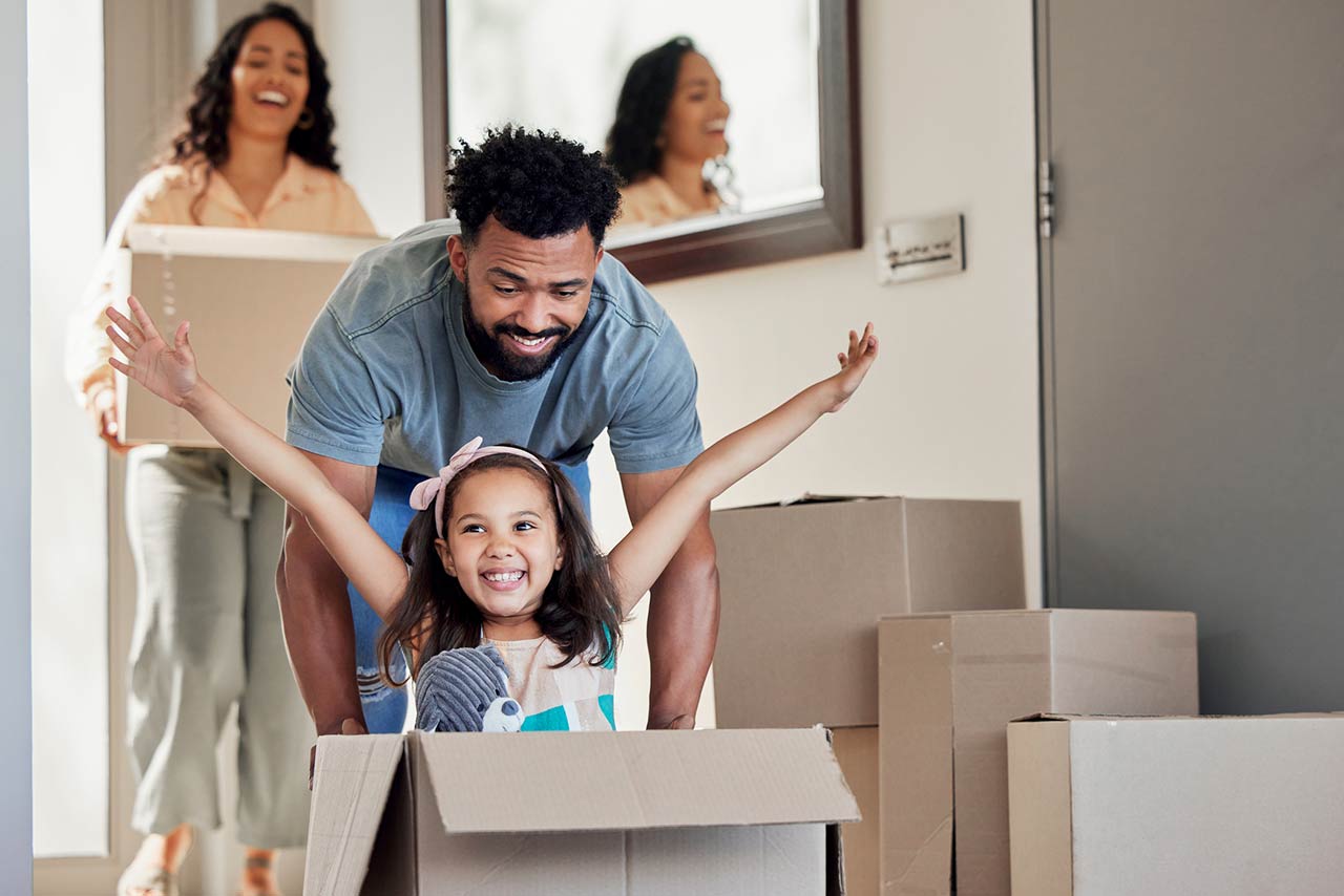 A young father having fun with his daughter while pushing her in a moving box