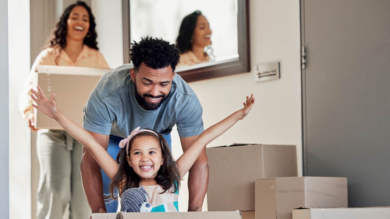 A young father having fun with his daughter while pushing her in a moving box