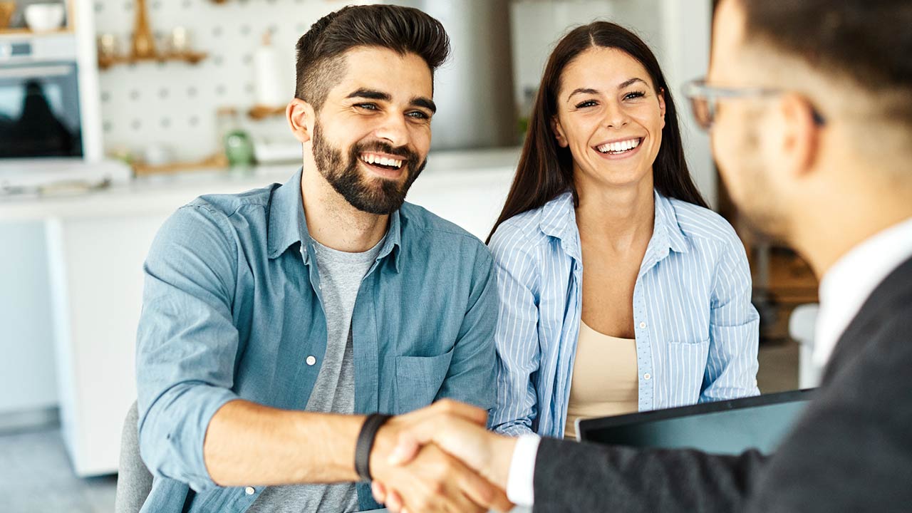 Real estate agent with couple shaking hands closing a deal and signing a contract
