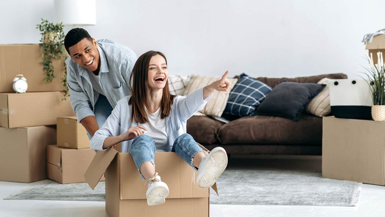Happy mixed race young family couple, bought their own house, they having fun on moving day