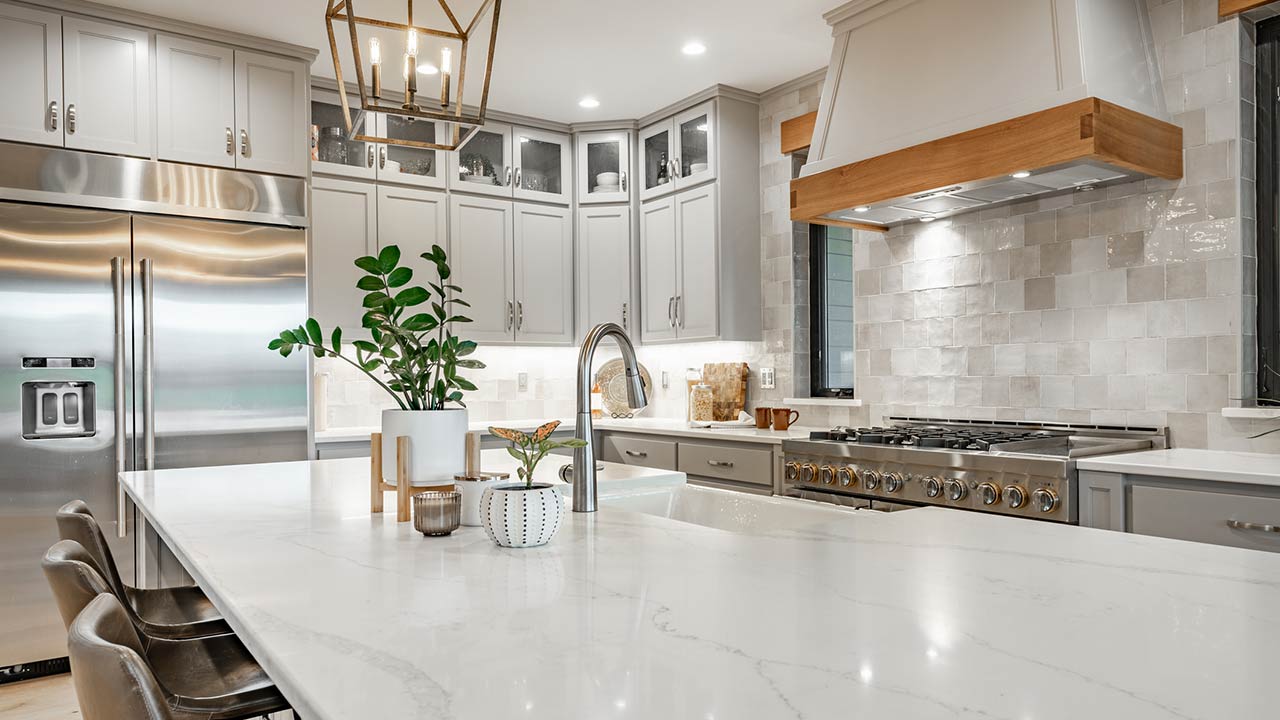 Large kithchen with white countertops, grey cabinets, stainless appliances, large white porcelain double sink farmhouse style