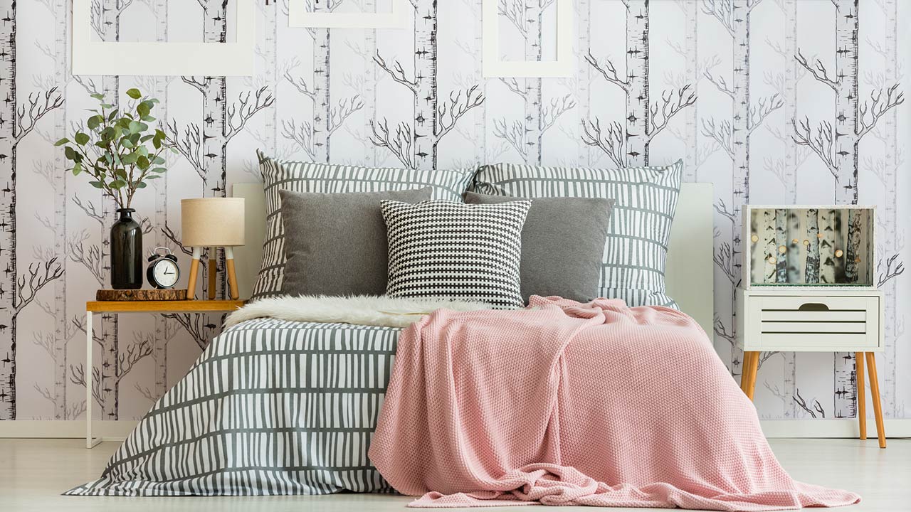 Feminine bedroom interior with forest inspired wallpaper and geometric bedding