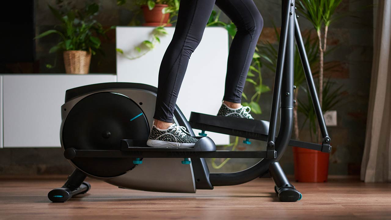 A womans legs training on smart elliptical trainer indoors at home in daylight with natural light