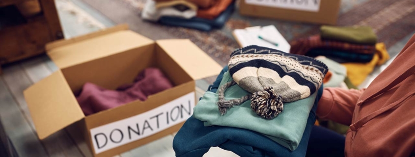 Close-up of woman packing boxes while donating her wardrobe for charity