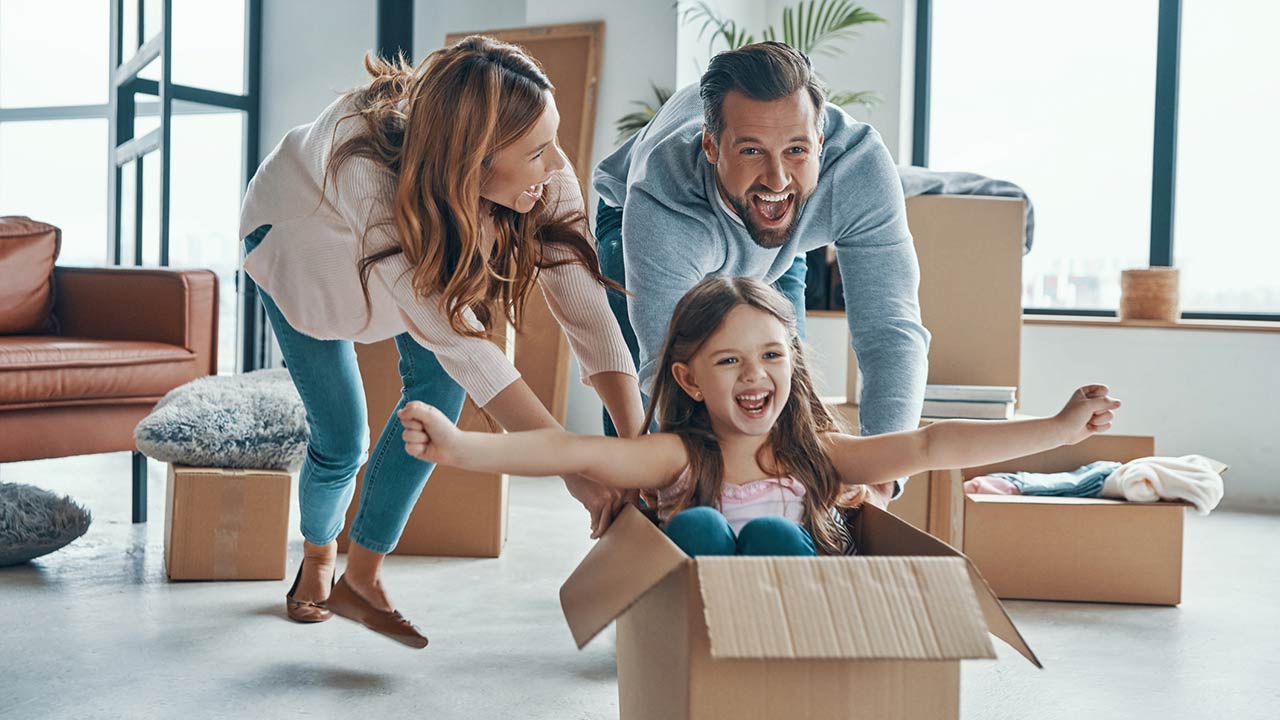 Cheerful young family smiling and unboxing their stuff while moving into a new apartment