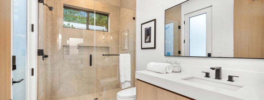 Modern bathroom with glass shower, wooden cabinets, and sleek fixtures in a bright, minimalist design