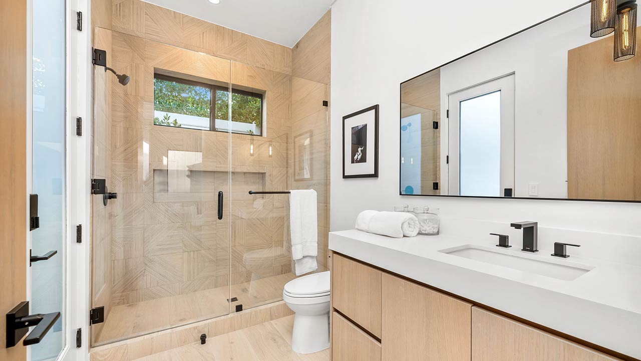 Modern bathroom with glass shower, wooden cabinets, and sleek fixtures in a bright, minimalist design
