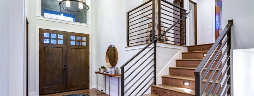 Chic entrance foyer with high ceiling and wide staircase with lights and contemporary railing